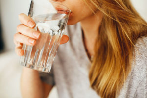 woman holding a glass of drinking water to her mouth